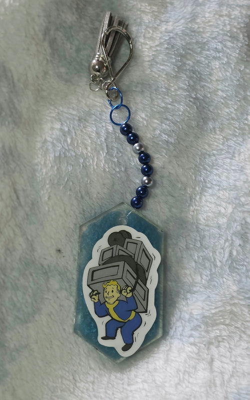 Keychain with Vault Boy holding a chest on a textured gray background